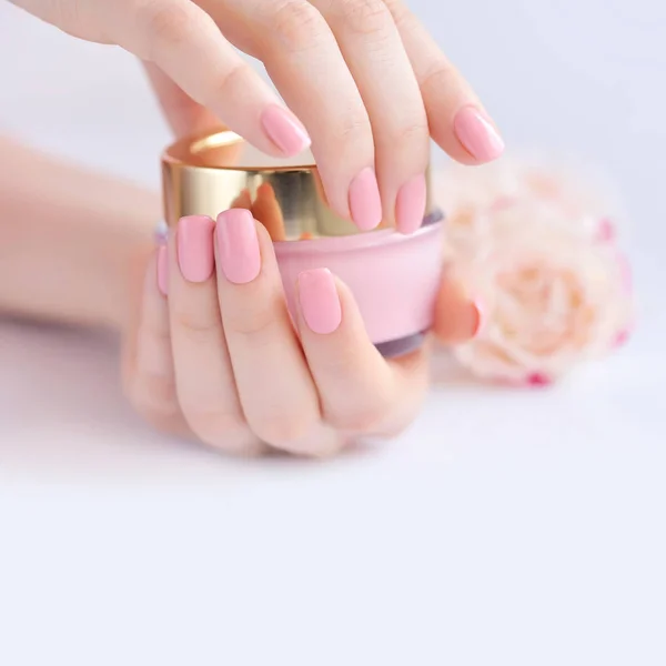 Ruce ženy s růžovými manikúra se smetanou — Stock fotografie