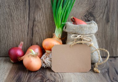 Boş kağıt etiket rustik ahşap arka plan üzerinde renkli soğan ile