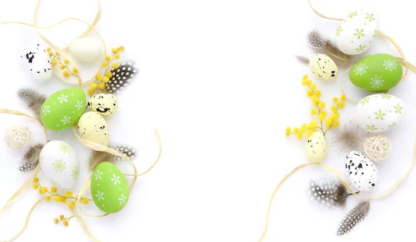 Easter eggs and mimosa flowers on white background with space for your text. Top view. Stock Photo