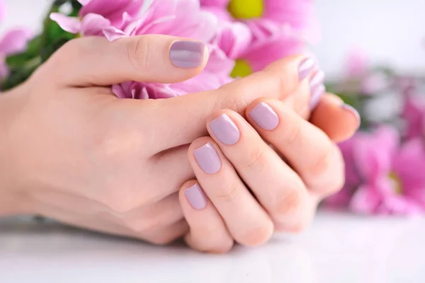 Mãos de uma mulher com manicure rosa em pregos e flores rosa — Fotografia de Stock