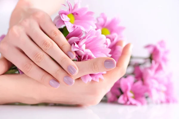 Handen van een vrouw met roze manicure nagels en roze bloemen — Stockfoto