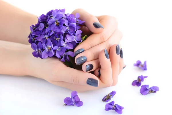 与黑暗修指甲指甲和束紫罗兰白色背景上一个女人的手 — 图库照片