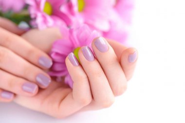 Pembe manikür çivi ve pembe çiçekler ile bir kadının elleri