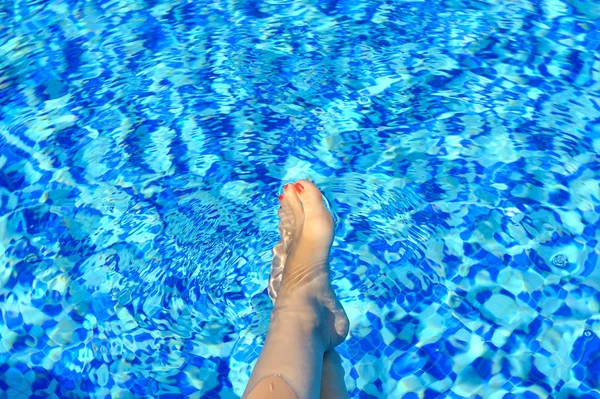 Vrouw voeten in zwembad op een warme zomerdag — Stockfoto