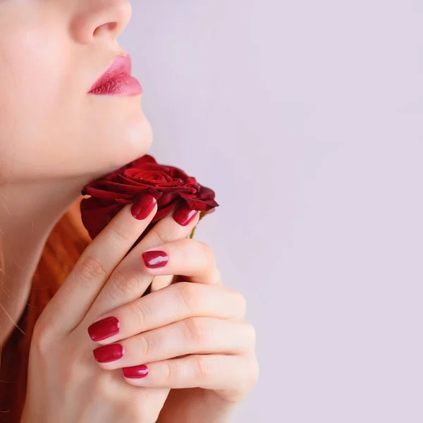 Retrato con flor de rosa roja. Labios rojos y uñas. Hermosa joven pelirroja . —  Fotos de Stock