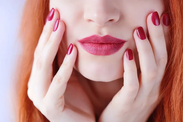 Mooie roodharige jonge vrouw met rode manicure, lippenstift dezelfde kleur. Close-up van portret. — Stockfoto