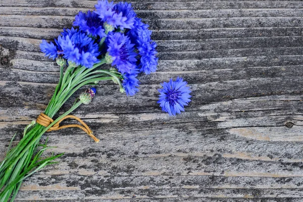 Flores azuis de girassol (Centaurea cyanus) em uma mesa de madeira velha. Vista superior . — Fotografia de Stock