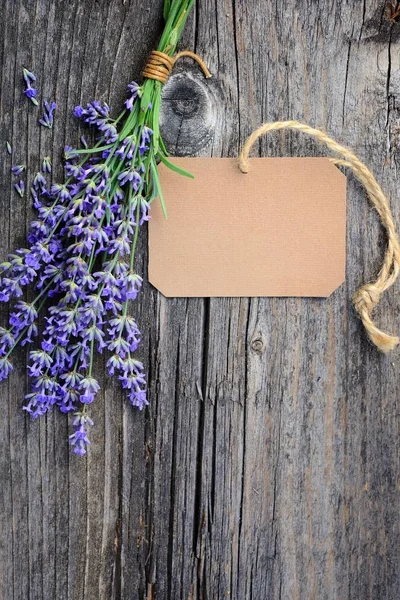 Flores de lavanda (Lavandula) con etiqueta de papel en una mesa de madera vieja —  Fotos de Stock