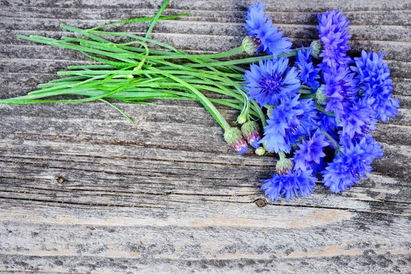 Flores azuis de girassol (Centaurea cyanus) em uma mesa de madeira velha. Vista superior . — Fotografia de Stock