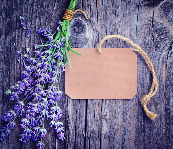 Flores de lavanda (Lavandula) con etiqueta de papel en una mesa de madera vieja. Foto de arte en tono púrpura . — Foto de Stock