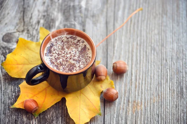 Koffiekopje op de daling van de herfst bladeren en houten oppervlak achtergrond — Stockfoto
