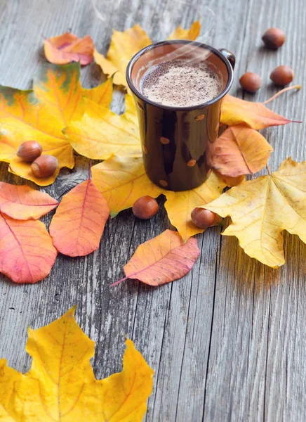 Tasse à café sur les feuilles d'automne d'automne et fond de surface en bois — Photo