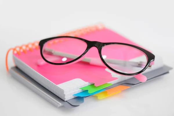 Gafas de ojo con cuaderno espiral rosa sobre fondo blanco — Foto de Stock