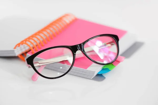 Gafas de ojo con cuaderno espiral rosa sobre fondo blanco — Foto de Stock