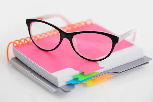Óculos de olho com caderno espiral rosa no fundo branco — Fotografia de Stock