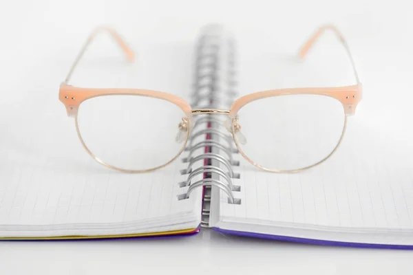 Óculos de olho com caderno em espiral em branco aberto no fundo branco — Fotografia de Stock