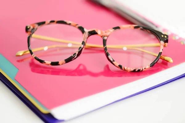 Brille mit rosa Spiralheft auf weißem Hintergrund — Stockfoto