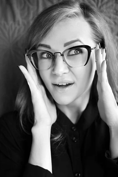 Retrato de mulher jovem sorrindo e segurando óculos. Foto em preto e branco — Fotografia de Stock