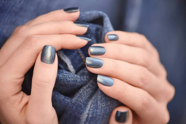 Mani con unghie blu scuro curati su jeans sfondo tessile — Foto Stock