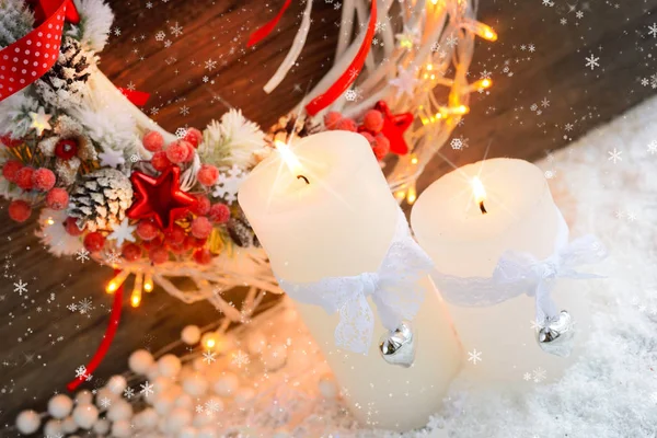 Witte kaarsen in de sneeuw met kerst krans en kerstverlichting. — Stockfoto