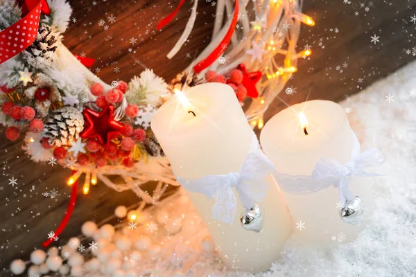 Velas blancas en la nieve con corona de Navidad y luces de Navidad . — Foto de Stock