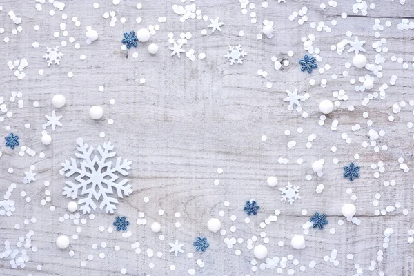 Snowflakes and confetti on a light wooden background — Stock Photo, Image