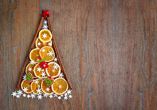 Albero di Natale di fette di arancio, fiocchi di neve e decorazioni natalizie su sfondo di legno — Foto Stock