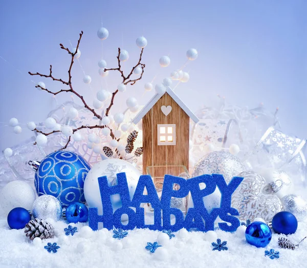 S pozdravem "Happy Holidays", dekorační koule a dům hraček na pozadí vánočních světel. — Stock fotografie
