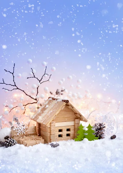 Paisaje decorativo navideño con casita de juguete en nieve, regalos y decoraciones sobre fondo de luces navideñas —  Fotos de Stock