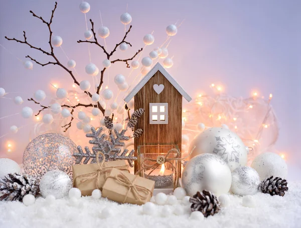 Composición navideña con bolas decorativas, casita de juguete y vela sobre nieve —  Fotos de Stock