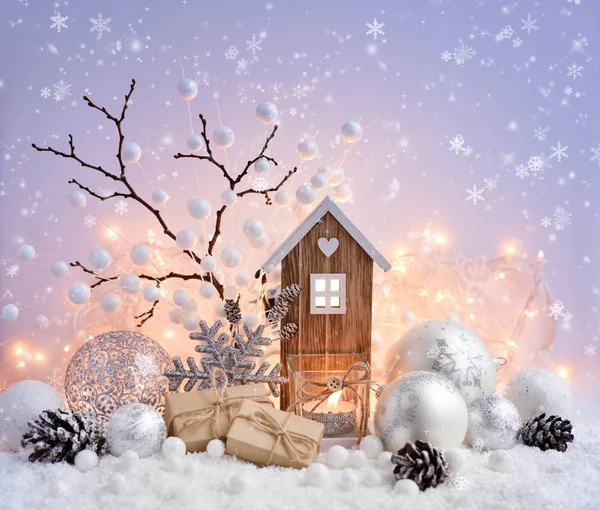 Composición navideña con bolas decorativas, casita de juguete y vela sobre nieve — Foto de Stock