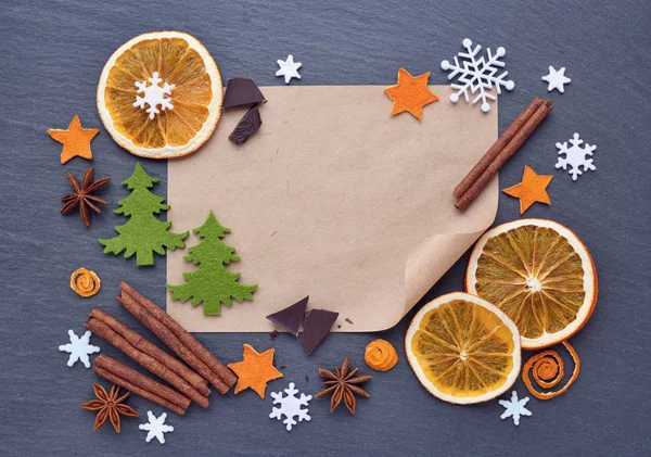 Weihnachten Hintergrund mit Lebkuchen, Schneeflocken, Gewürzen, Schokolade und leerem Blatt Papier für Ihre Glückwünsche auf dunklen Tisch — Stockfoto