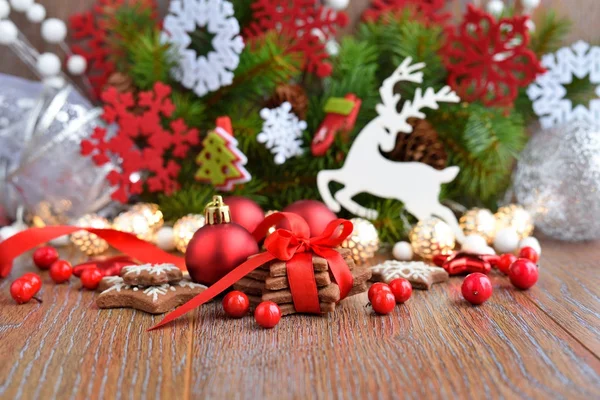 Kerstkoekjes met feestelijke decoraties en vuren takken op een houten tafel — Stockfoto