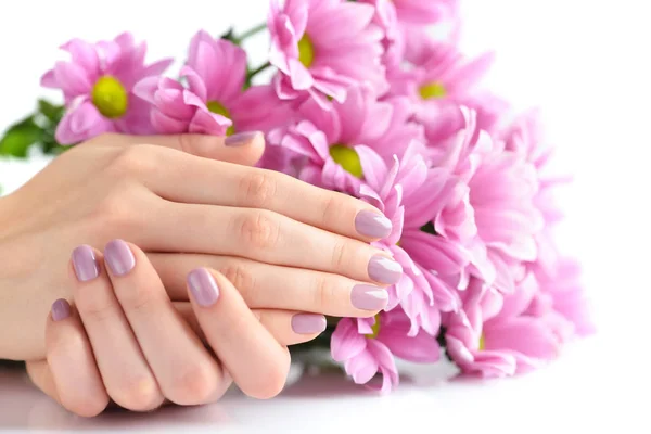 Händerna på en kvinna med rosa manikyr på naglarna och rosa blommor på vit bakgrund — Stockfoto