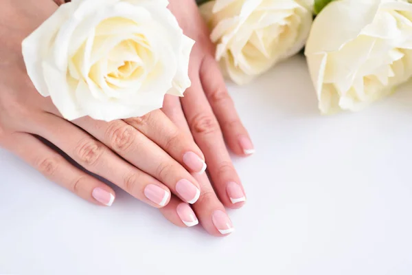 Hände einer Frau mit schöner französischer Maniküre und weißen Rosen — Stockfoto