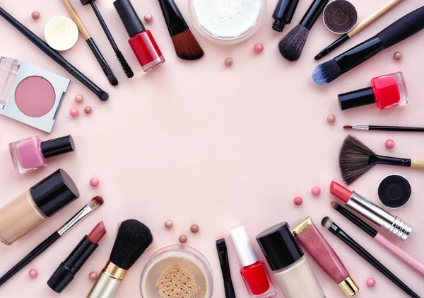 Cepillo de maquillaje y cosméticos decorativos dispuestos alrededor de un espacio en blanco sobre un fondo rosa pastel —  Fotos de Stock