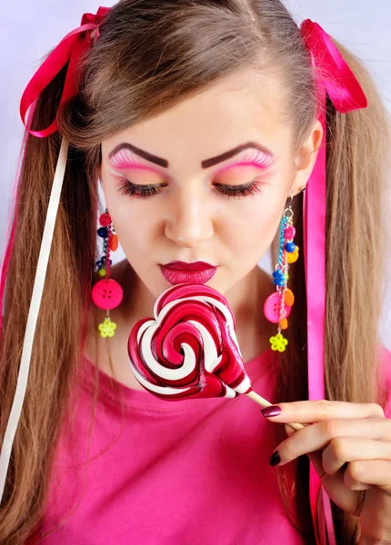 Mulher bonita com maquiagem criativa mordendo pirulito colorido — Fotografia de Stock