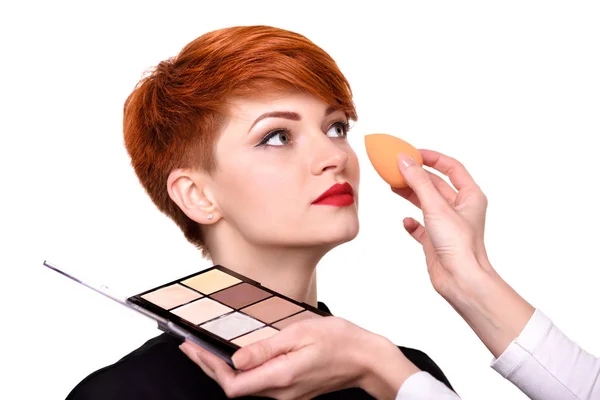 Maquillaje artista aplicando la fundación en la cara de la mujer joven usando esponja — Foto de Stock