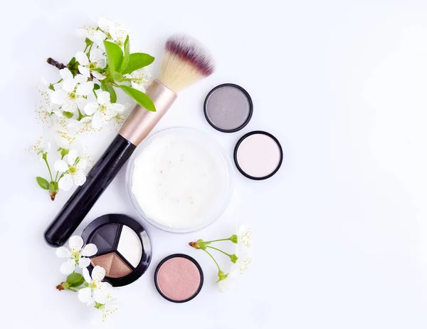 Cepillo de maquillaje y cosméticos decorativos con rama en flor sobre fondo blanco — Foto de Stock