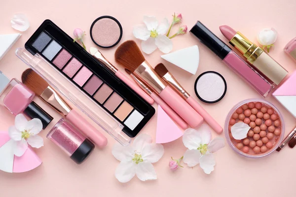 Cepillo de maquillaje y cosméticos decorativos con flor de manzana sobre fondo rosa —  Fotos de Stock