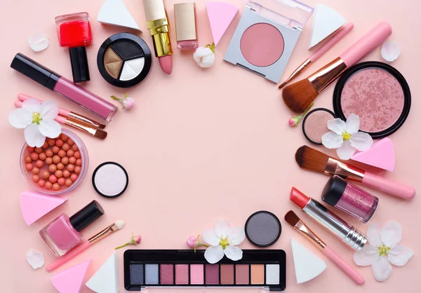 Кисть для макияжа и декоративная косметика с цветом яблока расположены вокруг пустого пространства на пастельно-розовом фоне — стоковое фото
