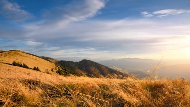 Dağlarda gün batımı. Parlak otlarla dolu sonbahar akşamı manzarası