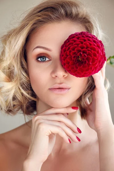 Portret młodej blondynki z czerwonym kwiatem w dłoni, ukrywającej oko — Zdjęcie stockowe
