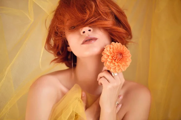 Portret młodej, pięknej rudowłosej kobiety z pomarańczowym kwiatem — Zdjęcie stockowe