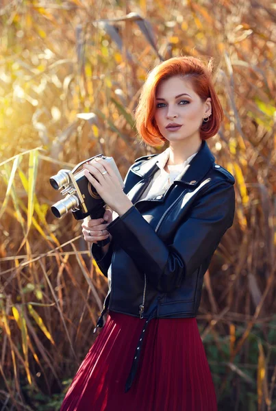 Mooie jonge roodharige vrouw houdt een videocamera — Stockfoto