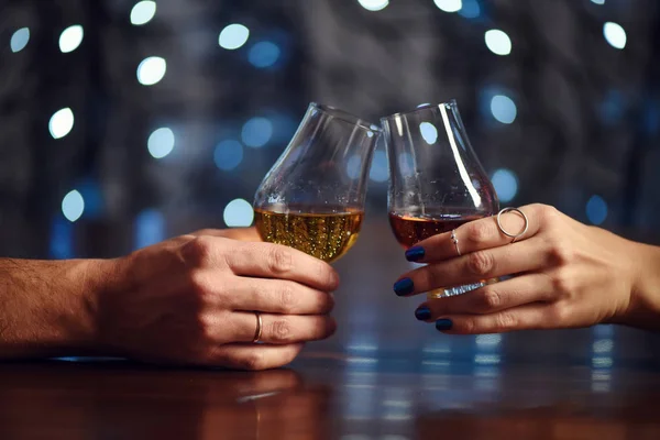 A couple makes a toast with two glasses of whiskey on festive background — Stock Photo, Image