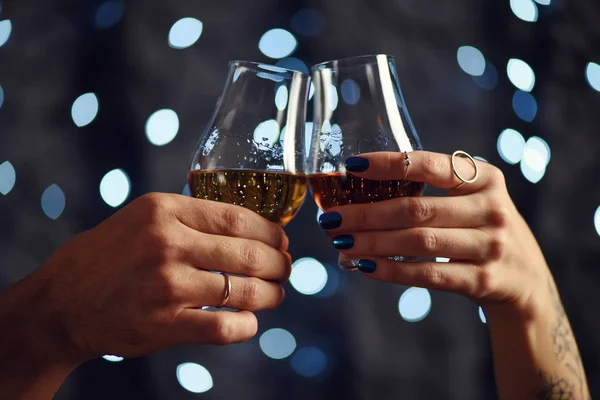 Ett par gör en skål med två glas whisky på festlig bakgrund — Stockfoto