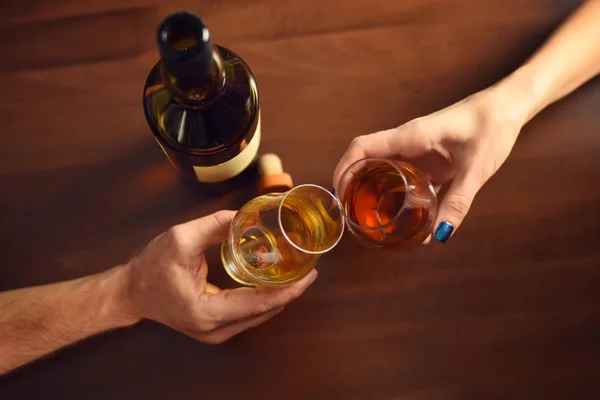 A couple makes a toast with two glasses of whiskey on wooden table — Stock Photo, Image