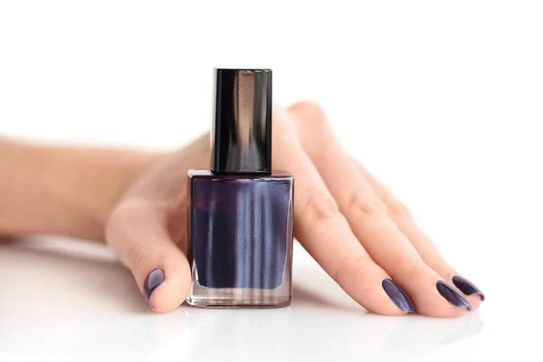 Mano de una mujer con manicura oscura y botella de esmalte de uñas — Foto de Stock