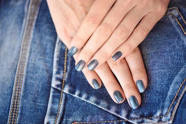 Mãos com unhas de manicure azul escuro sobre fundo têxtil jeans — Fotografia de Stock